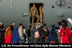 Refugiați afgani se pregătesc de îmbarcare într-un avion militar la baza aeriană americană Al Udeid, din Qatar, 22 august 2021.