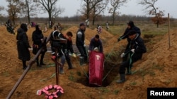 A coffin containing the body of a local resident in Kherson who died during Russian occupation is lowered into a grave on November 17 following the liberation of the city by Ukrainian forces. 