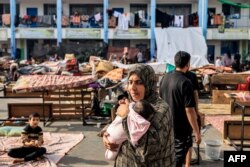 Žena sa djetetom na igralištu škole koju vodi UNRWA, a koja je pretvorena u sklonište za raseljene Palestince u Khan Yunisu u južnom pojasu Gaze 25. oktobra, 2023.