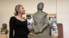 Dorina Roșca pozând alături de monumentul femeii migrante. 