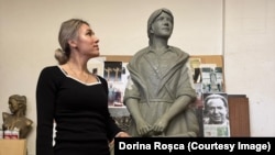 Dorina Roșca pozând alături de monumentul femeii migrante. 