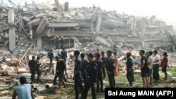 Люди наблюдают, как спасатели ищут выживших, оказавшихся под обломками обрушившегося здания в городе Мандалай, Мьянма, 29 марта 2025 года