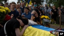 Mama lui Oleksandr Mihailenko, Svitlana, și bunica lui, Nadia, plâng în fața sicriului în Jukin, Ucraina, la 11 august. Oleksandr, militar în armata ucraineană, a murit în luptele din regiunea Harkov în luna martie a acestui an, dar trupul său a fost identificat abia recent.