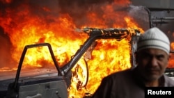 Demonstrant u Kairu ispred zapaljenog policijskog vozila, 28. januar 2011.