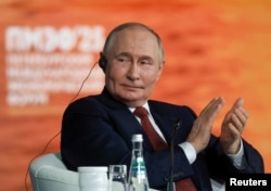 Președintele Vladimir Putin aplaudă în timpul unei sesiuni plenare a Forumului Economic Internațional de la Sankt Petersburg pe 20 iunie.