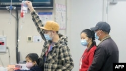 Родственник доставленного в больницу в китайском Ханчжоу ребенка держит капельницу. 6 января 2025 года. Пекин признал рост случаев человеческого метапневмовируса (HMPV), особенно среди детей, и объяснил это сезонным всплеском